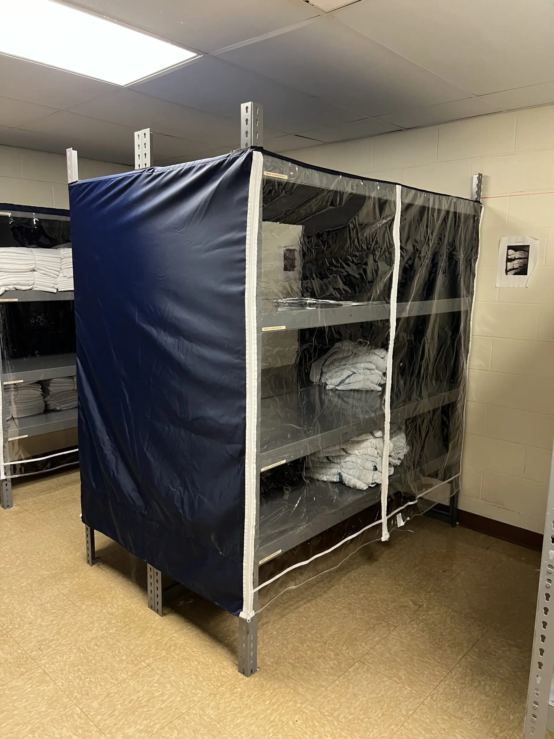 Shelving unit covered with clear plastic and linens