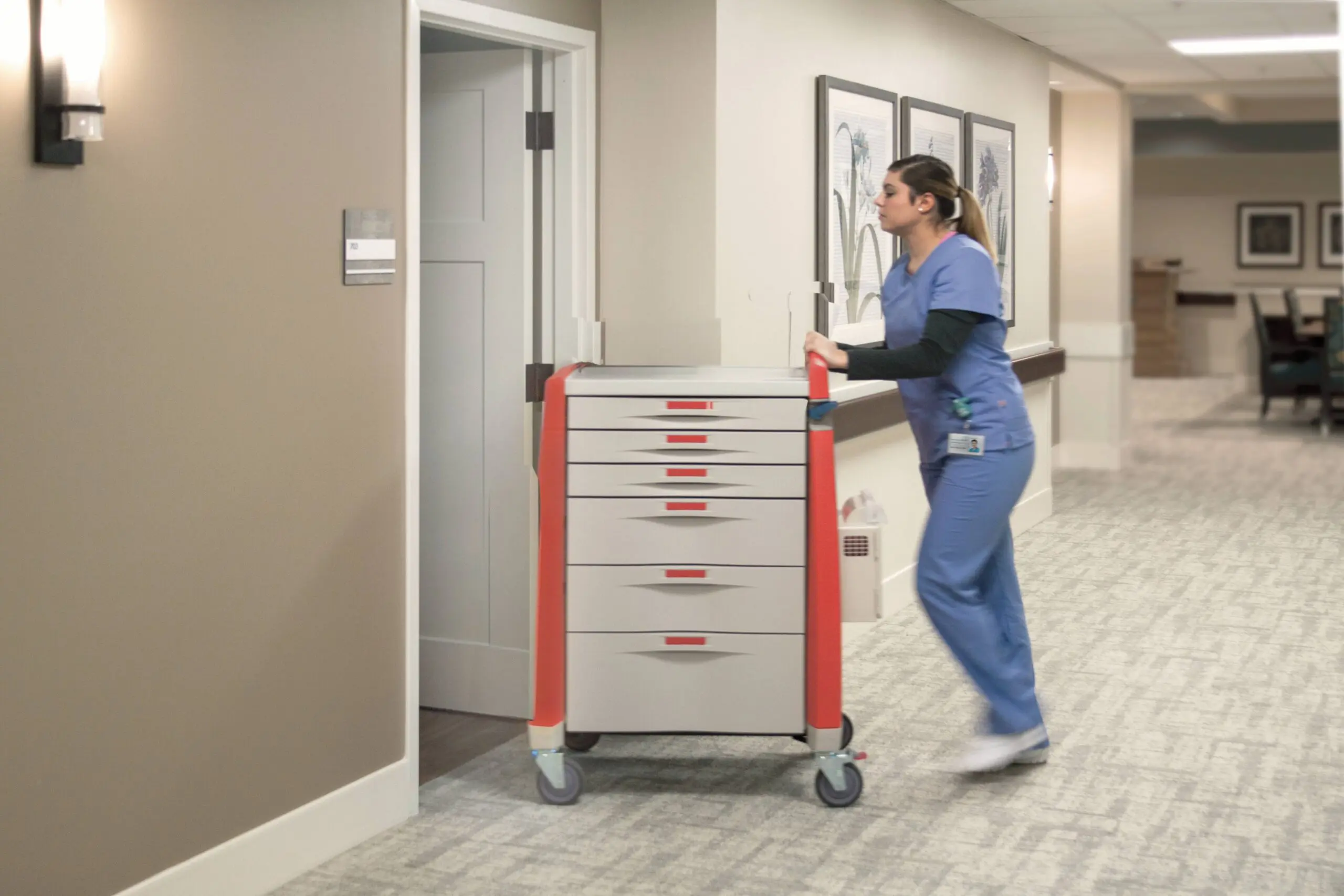 Nurse pushing medical cart down hospital corridor