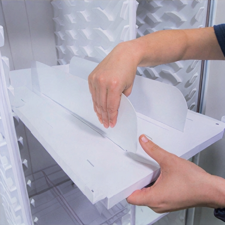 Person inserting a transparent plastic cover into a white tray.